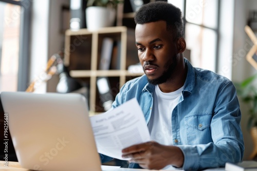 A busy young professional businessman checks documents on his laptop in his office. Serious business accounting experts in the workplace read legal documents overview of company documents.