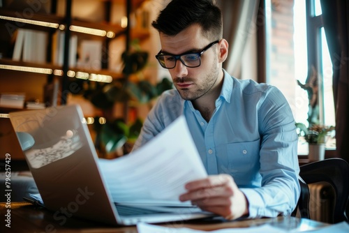 A busy young professional businessman checks documents on his laptop in his office. Serious business accounting experts in the workplace read legal documents overview of company documents.
