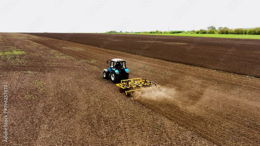 Aerial view of an agricultural tractor plowing a field on a warm spring day. Agricultural natural seasonal spring work. Concept of industrial work and agricultural transport in the open air. Aerial view of an agricultural tractor plowing a field on a warm spring day. Agricultural natural seasonal spring work. Concept of industrial work and agricultural transport in the open air.