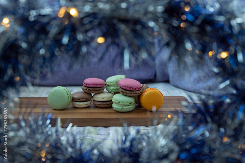 Close up delicious macaroon cookies in fresh mint green vanilla beige chocolate brown orange and pink colors. Blue bokeh shining blurred foreground decor. Contrast bright combination, bakery culinary.