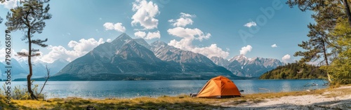 An orange tent is pitched on the shore of a lake, surrounded by a beautiful summer landscape