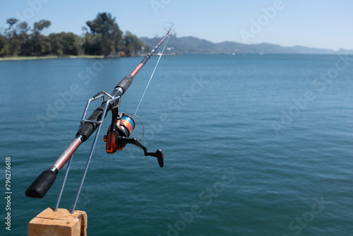 Fish rod mounted on a wooden spring rod holder with blurred background of water and landscape on horizon