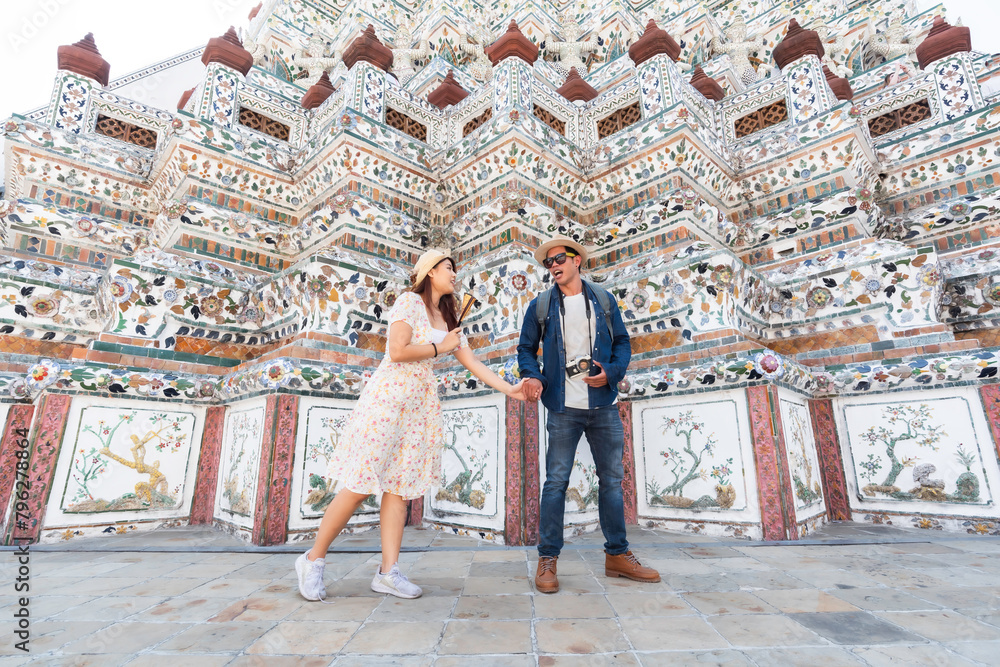 Asian couple happy tourists to travel on they holidays and holding in Wat Arun Temple in Bangkok, Thailand.holiday concept.