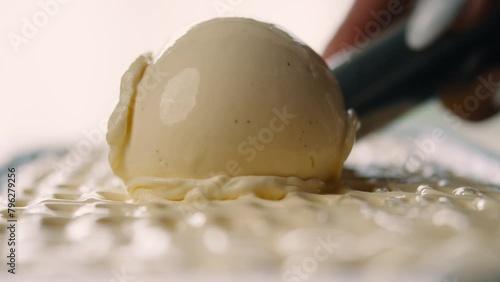 Person scooping up yellow ice cream from tray