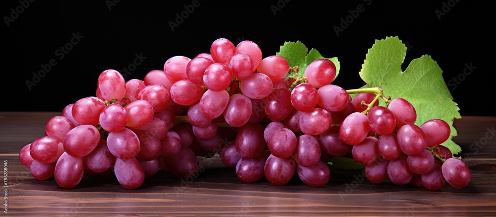 Fototapeta premium Fresh red grapes and leaves on wooden surface
