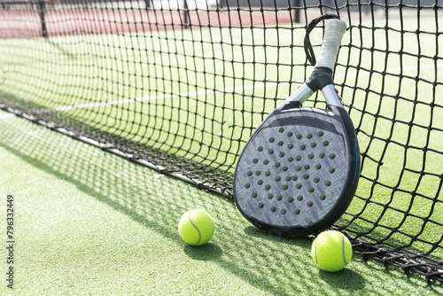 Padel racket and padel ball on a green court in the sunset