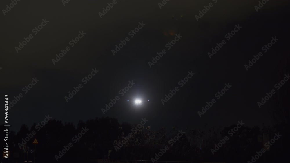 An airplane with bright lights descending against a dark night sky An airplane with bright lights descending against a dark night sky