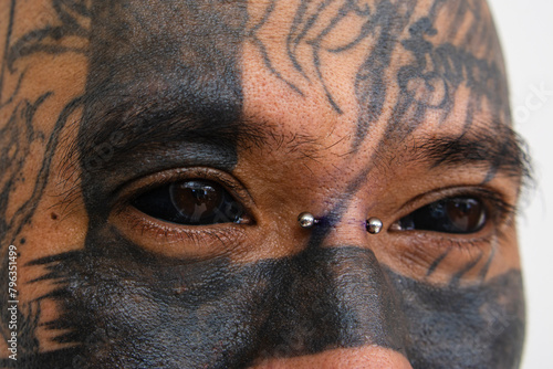 Closeup of a man with face tattoos showing off his black eye tattoos. A Blackened scleras. Scleral tattooing. photo