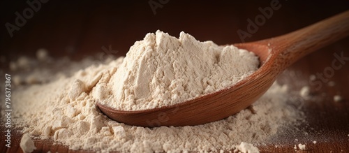 Wooden spoon scooping flour on table photo