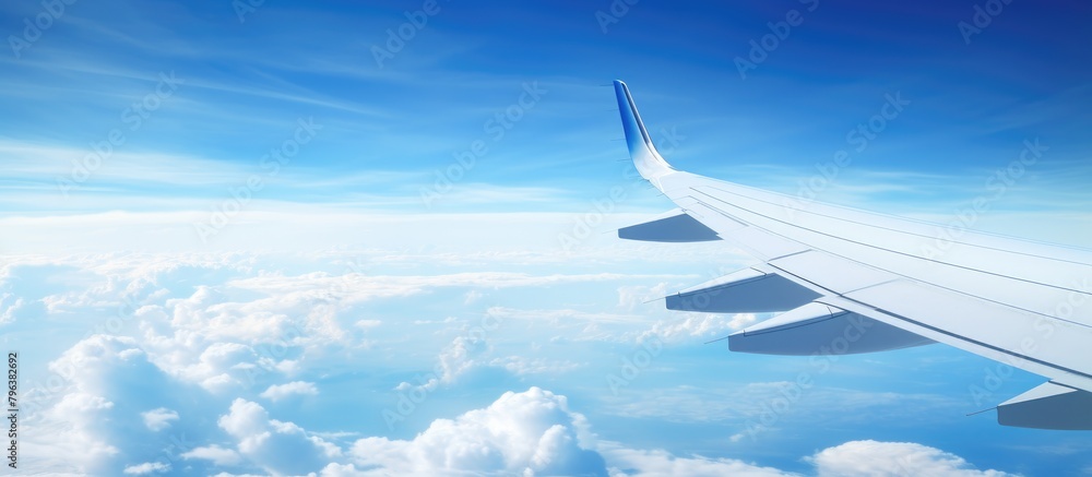Fototapeta premium Aerial view of airplane wing soaring over clouds