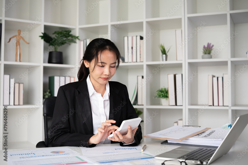 Asian female accountant Use a calculator to calculate business numbers on a white wooden table in the office. Asian female accountant Use a calculator to calculate business numbers on a white wooden table in the office.