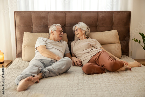 Senior couple laying down on a bed in a bedroom and relaxing.