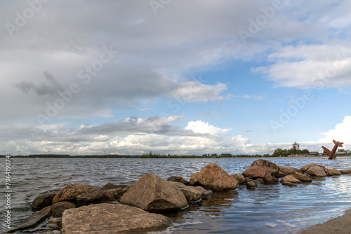 Boulders in the water of the Wolderwijd with the monument to Allied airmen near Harderwijk, Netherlands in the background © Emma