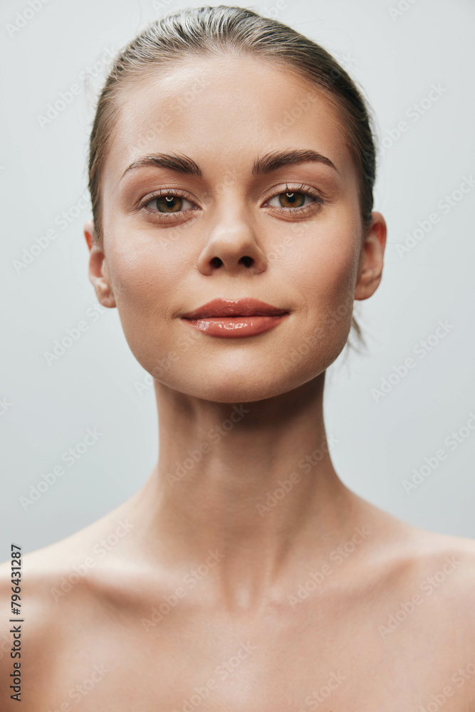 Beautiful young woman with serene expression looking directly at camera in front of gray background, isolated portrait shot Beautiful young woman with serene expression looking directly at camera in front of gray background, isolated portrait shot