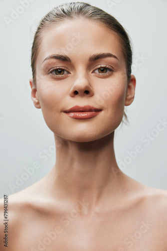 Beautiful young woman with serene expression looking directly at camera in front of gray background, isolated portrait shot © SHOTPRIME STUDIO