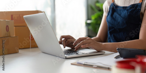 Woman in an online store check the customer address and package information on the laptop. Online shopping concept