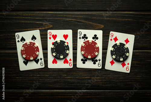 A gambling game of poker with a lucky winning combination of four of a kind or quads. Playing cards and chips on a black vintage casino table