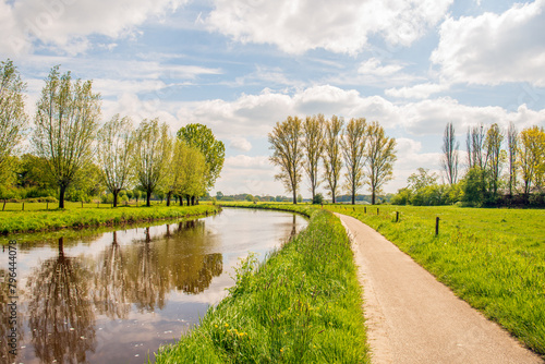 Picturesque landscape a small river in springtime with a cycling and walking path along the water. The photo was taken in the outskirts of a small village in the province of North Brabant.
