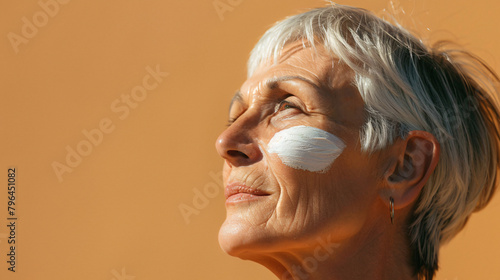 Senior woman with sunscreen cream on her face 