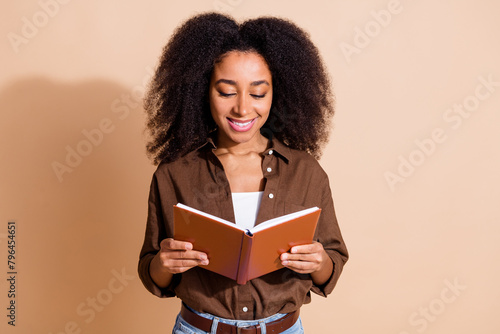 Photo of intelligent positive girl with perming coiffure wear brown blouse read interesting novel isolated on pastel color background