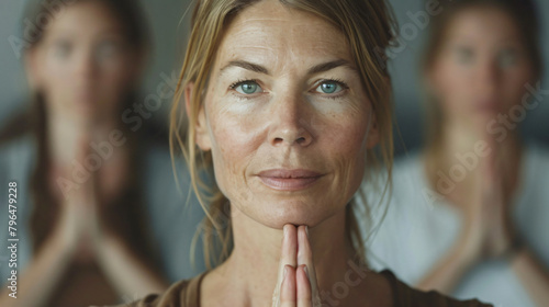 Close-up portrait of a middle-aged woman leading a yoga session with other participants. Emphasizing the role of the yoga instructor.