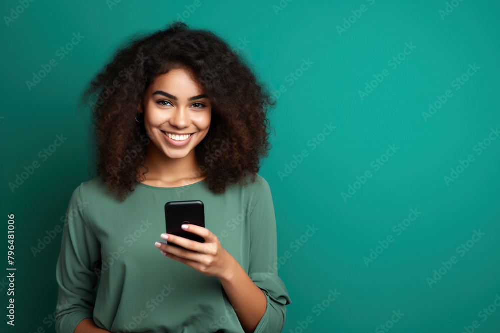 Happy Latin American woman with phone on Emerald studio background