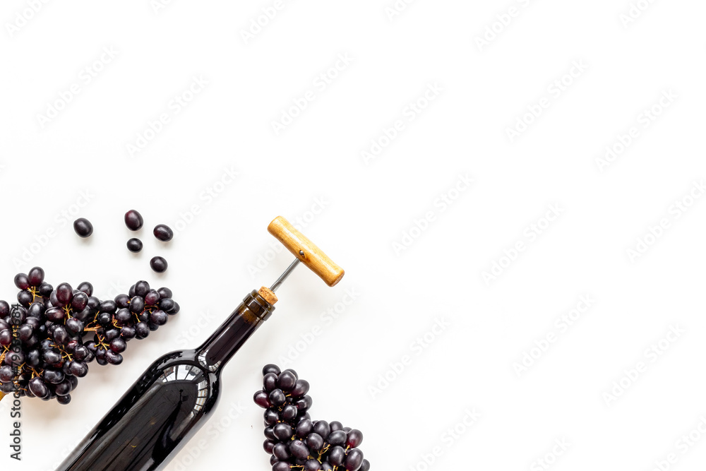 Fototapeta premium Red wine in the bottle with bunch of grapes and corkscrew, top view