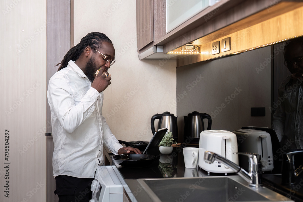 African American man using digital tablet at the kitchen reading social media internet, typing text or shopping online. Freelancer remotely working online at home African American man using digital tablet at the kitchen reading social media internet, typing text or shopping online. Freelancer remotely working online at home