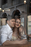 Romantic young valentine couple in love hugging in cafe. Candid view through window glass.