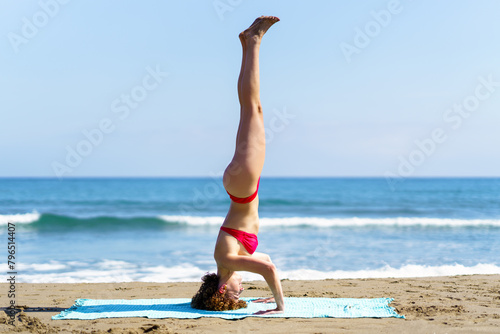 Calm lady balancing in headstand on seashore
