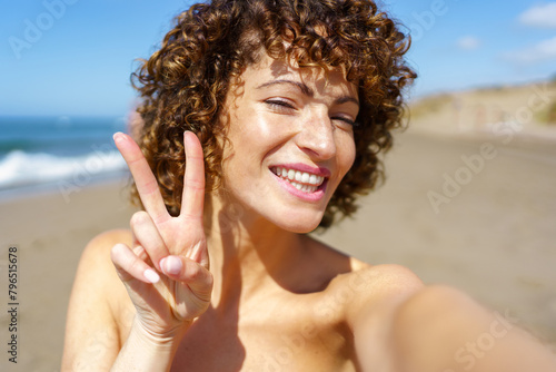 Happy woman showing V sign on beach