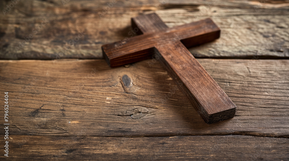 There is a small, wooden cross laying on a wooden table.

