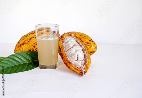 Fresh cacao water in glass and half sliced ripe yellow cacao pod with white cocoa seed, Cacao juice in glass  on white wooden background