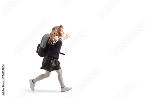 Full length profile shot of a schoolgirl in a uniform carrying a backpack and running with arms wide open
