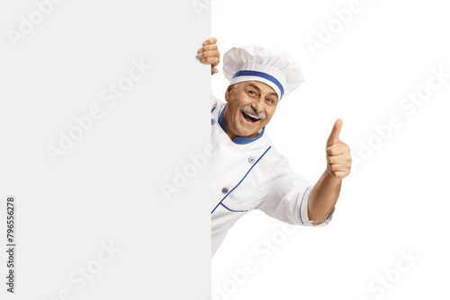 Mature male chef in a uniform gesturing thumbs up behind a blank panel