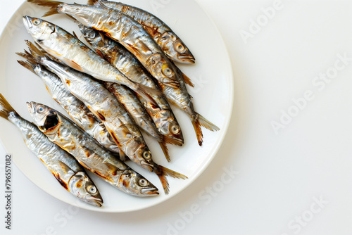 Cooked fish are served on a white plate, on a white background.