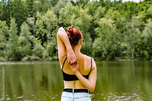 Back view of fitness slender fit girl woman practicing doing yoga gomukhasana,holding hands behind back,stretching in Cow Face Pose,river,relaxing.nature landscape.Triceps arms training photo