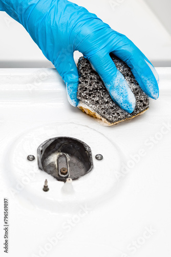 housewife washes a gas stove in the kitchen with a sponge, close-up