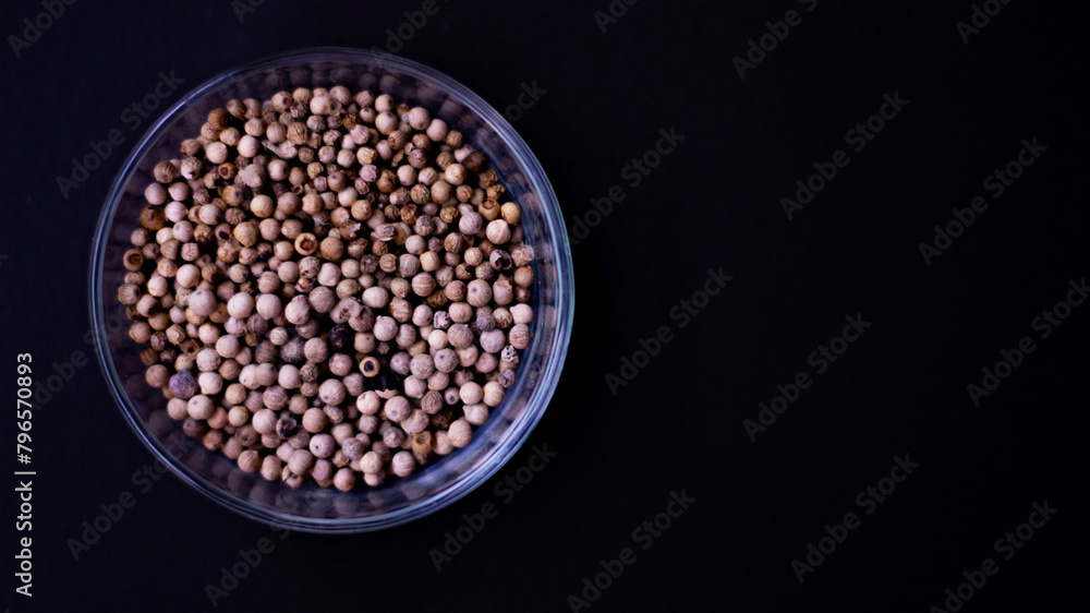 organic pepper dried white pepper corns in Indonesian in traditonal asian glass bowl on black background organic pepper dried white pepper corns in Indonesian in traditonal asian glass bowl on black background
