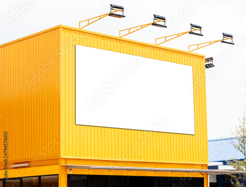 Mock up white background billboard on yellow building with spotlight. Clipping path for mockup