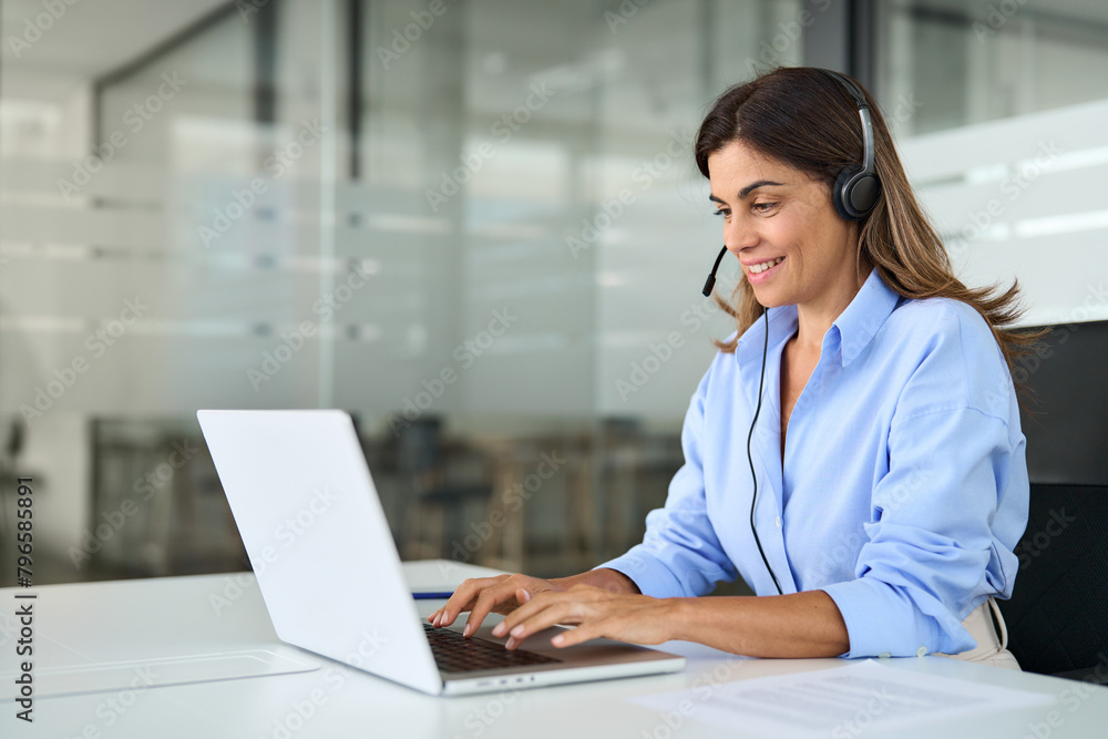 Busy mature business woman call center representative customer support agent helping client, smiling middle aged senior female operator wearing headset working using laptop computer in office. Busy mature business woman call center representative customer support agent helping client, smiling middle aged senior female operator wearing headset working using laptop computer in office.