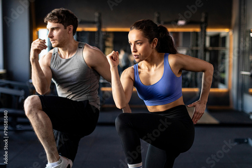 Focused sportive couple doing warm up exercises during fitness workout in modern gym