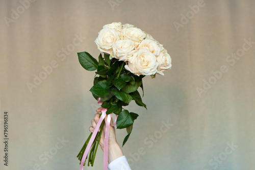 white roses in woman hands on brown. girl is holding bouquet of fresh roses