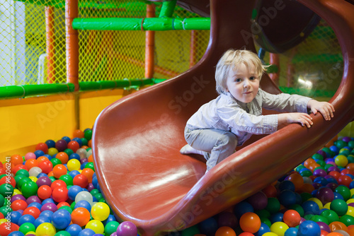 Toddler having fun in a green ball pit at the playground. Cute Kid Or Child Playing Colorful Balls on ball pit. toddler smiling