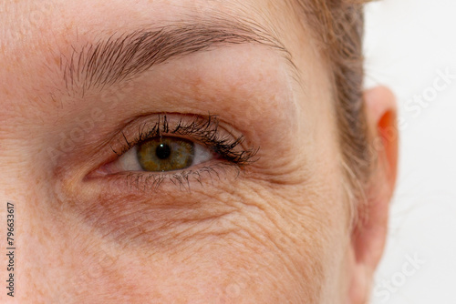 Close up cropped eye with wrinkles of middle aged caucasian woman looking at camera
