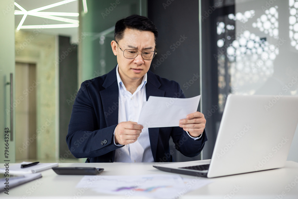 Businessman analyzing document at modern office desk Businessman analyzing document at modern office desk
