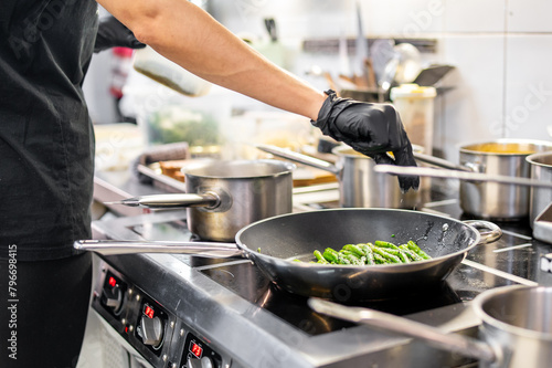 Professional chef sautéing fresh green vegetables in a dynamic kitchen environment, showcasing culinary skills and ingredients