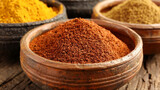 A bowl of spices is shown with a wooden table underneath. The spices are in different colors and sizes, and the bowl is filled to the brim. Concept of abundance and variety