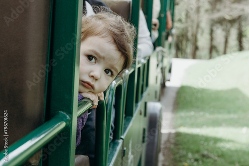 Portrait of a baby girl looking out of a train carriage.