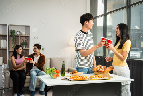 .Young Asian students gather with friends for a pizza party  laughing and sharing slices. Enjoying fast food delivery  they embody diversity and togetherness in a relaxed  enjoyable lifestyle.